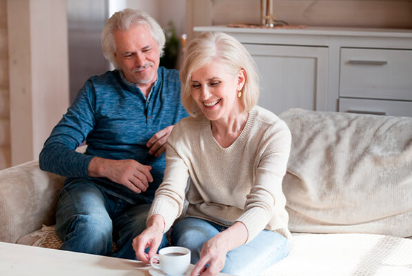 Elderly man and women having a chat and sitting on couch next to coffee table
